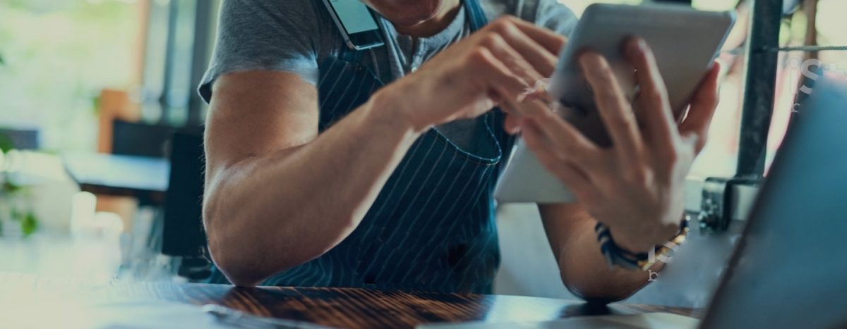 Person using a calculator in front of a computer while working on small business bookkeeping tasks.