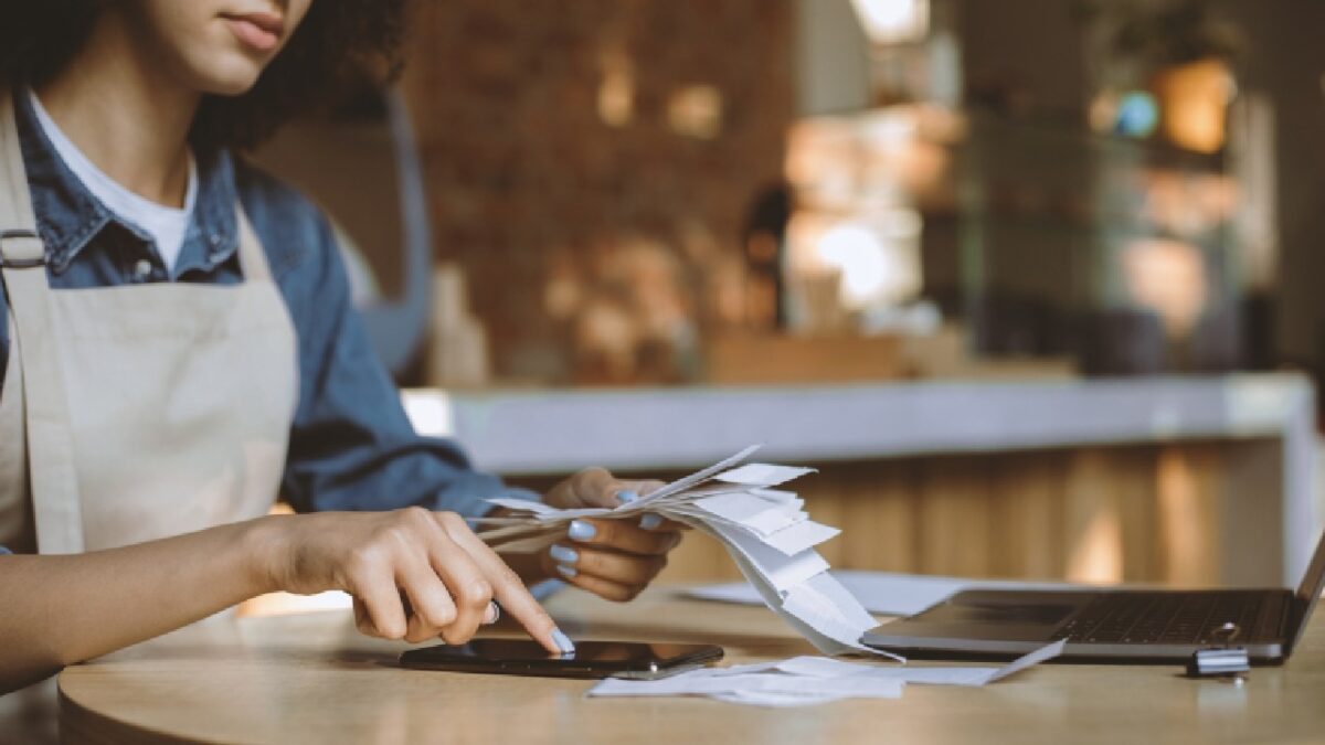 Small business owner sorting receipts and entering data as part of the month-end close process.