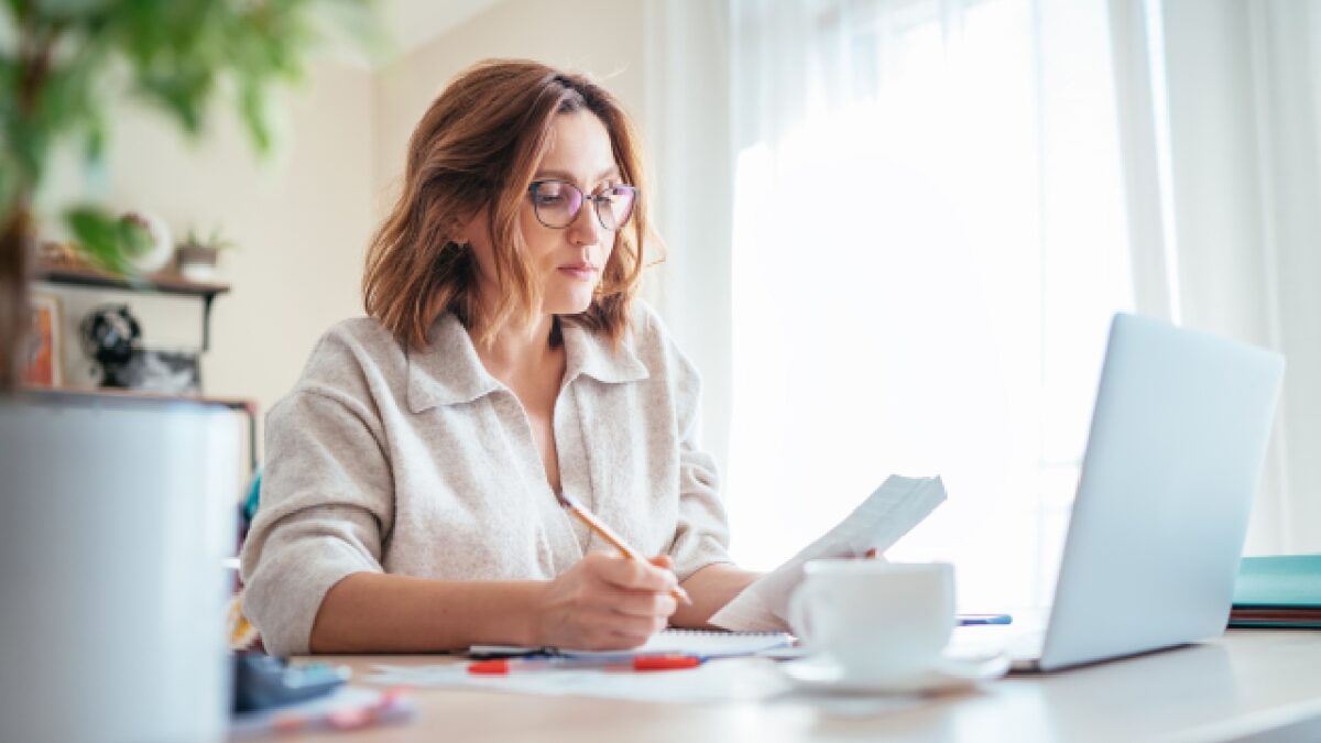 Small business owner preparing EOFY paperwork and financial records at desk using laptop and receipts for EOFY checklist planning.