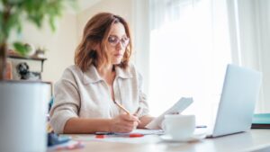 Small business owner preparing EOFY paperwork and financial records at desk using laptop and receipts for EOFY checklist planning.